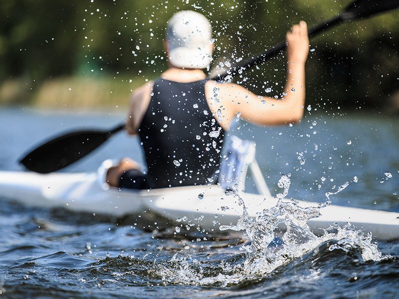 athlete at rowing kayak on lake during competition.splashing water in foreground